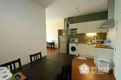 Modern kitchen with dining area, featuring washing machine and sleek appliances.