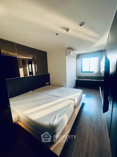Spacious modern bedroom with large windows and sleek wooden flooring, perfect for urban living.