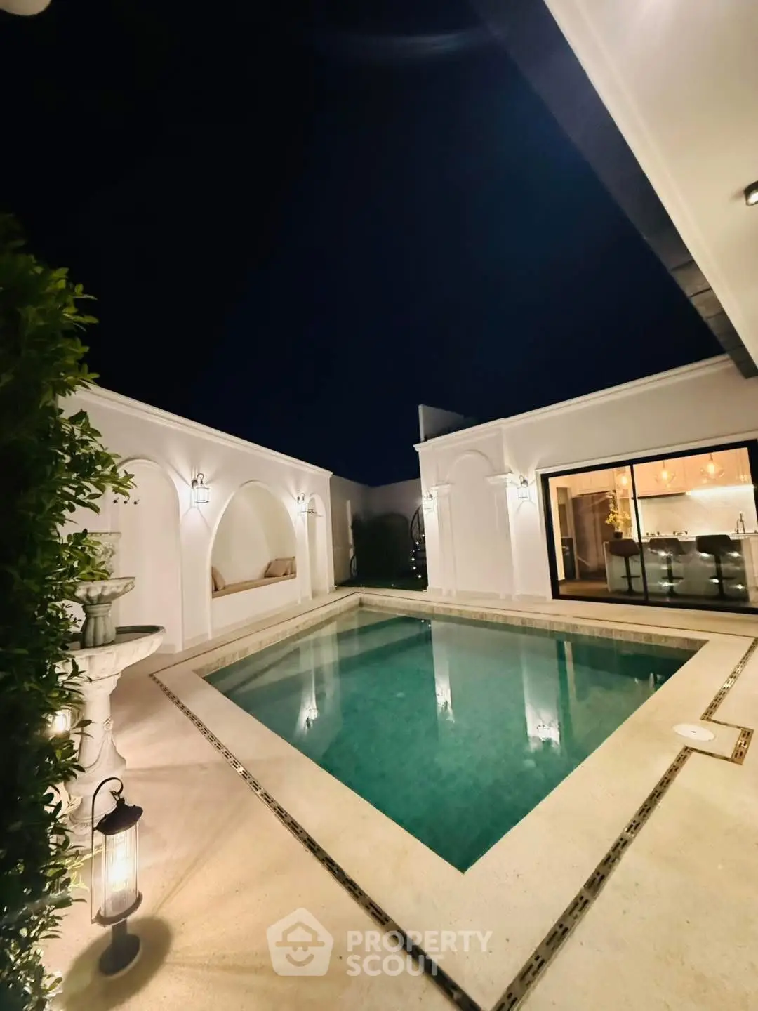 Luxurious night view of a private courtyard with a serene pool and elegant lighting.