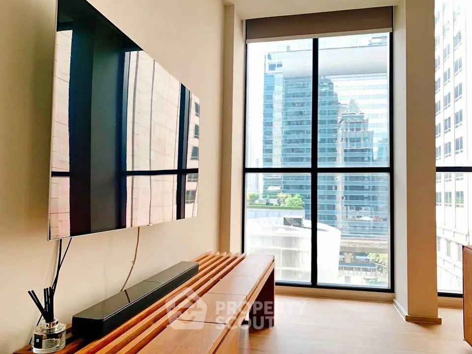 Modern living room with large window offering stunning city view and sleek wall-mounted TV.