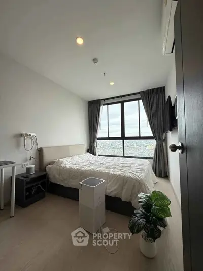 Modern bedroom with large window offering stunning city view, featuring minimalist decor and cozy ambiance.