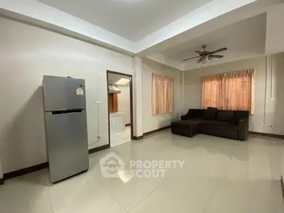 Spacious living room with modern fridge and cozy sofa, ideal for comfortable living.