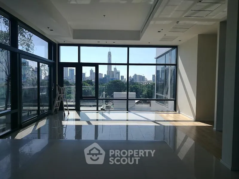 Spacious modern living room with floor-to-ceiling windows and stunning city skyline view.
