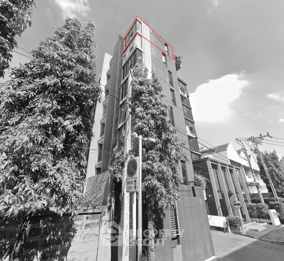 Modern multi-story building with lush greenery and sleek design in urban setting.