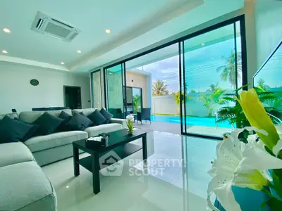 Luxurious living room with pool view, modern decor, and large glass doors opening to a tropical paradise.