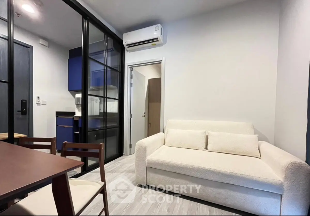 Modern living room with cozy white sofa and sleek glass partition in stylish apartment.