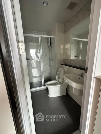 Modern bathroom with glass shower and sleek fixtures in contemporary apartment.