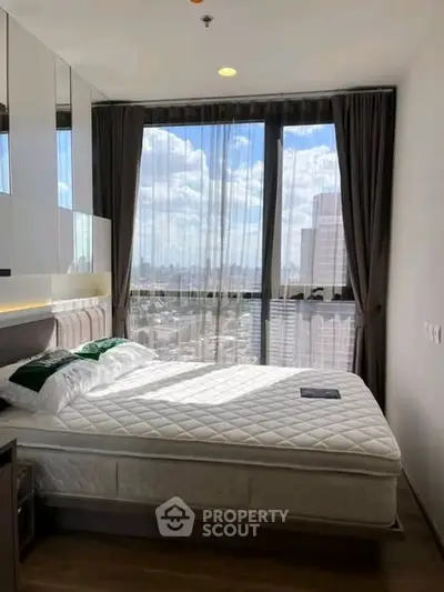Modern bedroom with large window offering stunning city view, featuring a comfortable bed and elegant decor.
