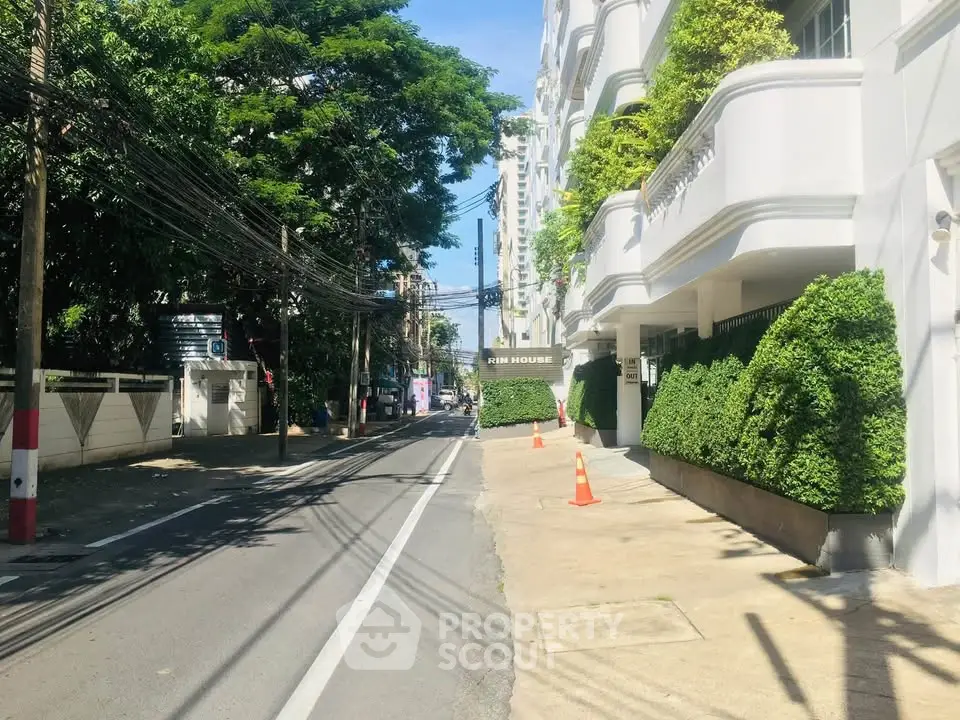 Charming street view with lush greenery and elegant building facade in a serene neighborhood.