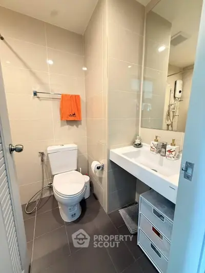 Modern bathroom with sleek fixtures and neutral tiles, featuring a spacious layout and contemporary design.