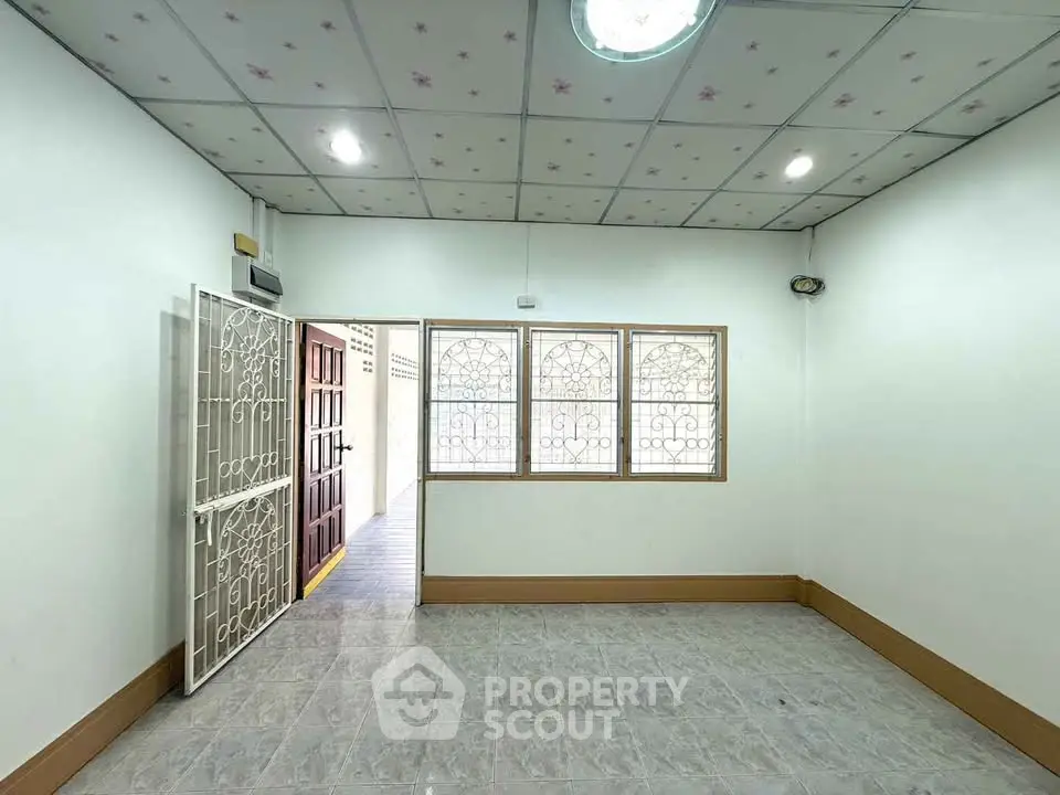 Spacious empty room with decorative ceiling and large windows in a well-lit interior.