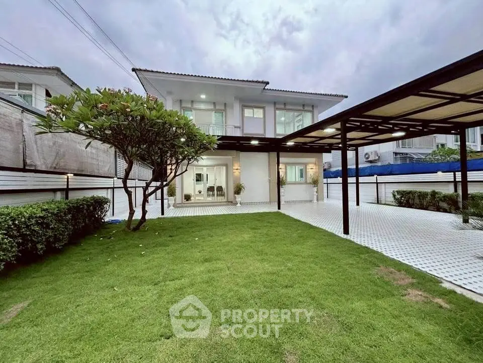 Spacious modern two-story house with lush green lawn and covered parking area.