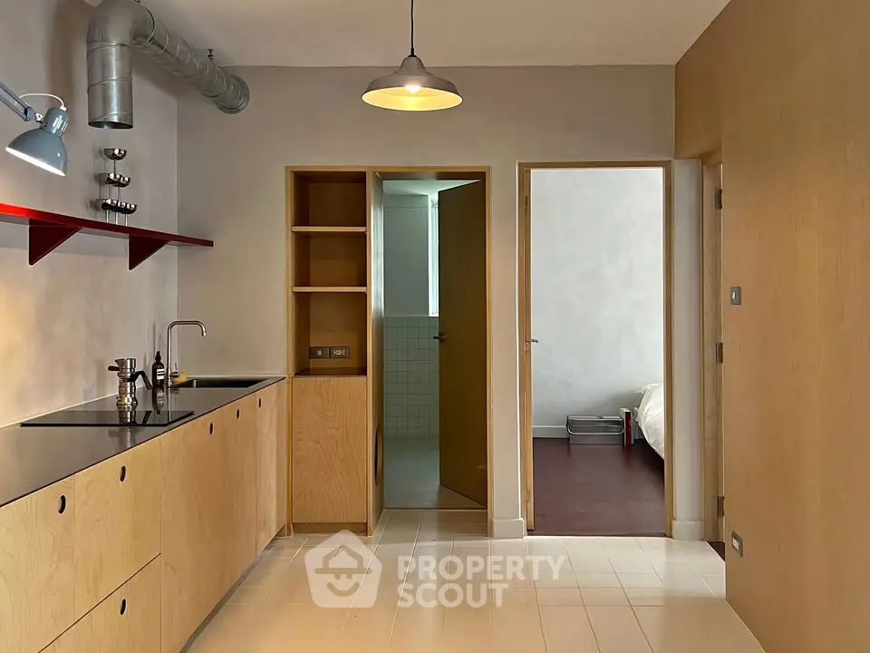 Modern kitchen with sleek cabinetry and open layout leading to a cozy bedroom.
