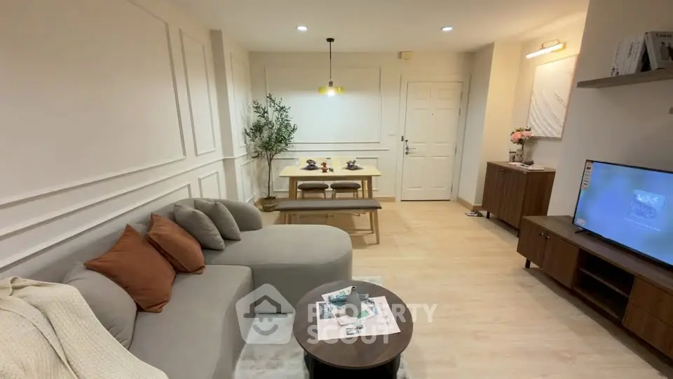 Modern living room with cozy sectional sofa and dining area, featuring elegant decor and warm lighting.