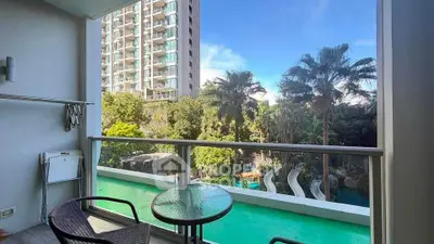 Spacious balcony with stunning view of lush greenery and modern high-rise building.