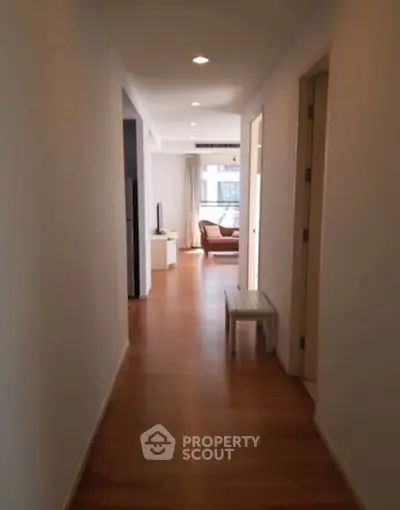 Spacious apartment hallway leading to a cozy living room with natural light.