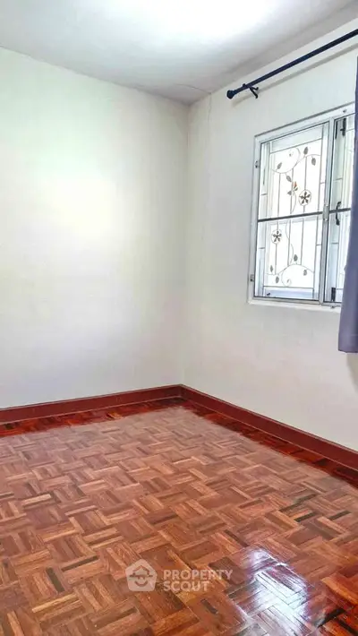 Spacious empty room with polished wooden floors and a window, ideal for customization.