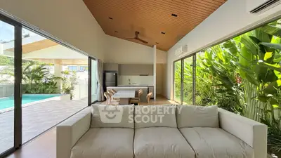 Luxurious open-plan living room with pool view and lush greenery