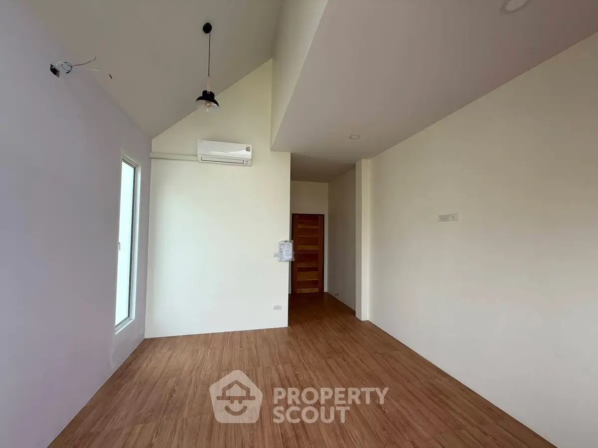 Spacious empty room with wooden flooring and high ceiling