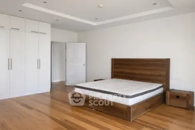 Spacious bedroom with wooden flooring and modern design in a luxury apartment.