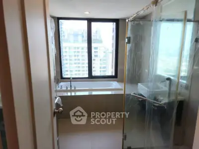 Modern bathroom with city view, featuring a bathtub and glass shower enclosure.