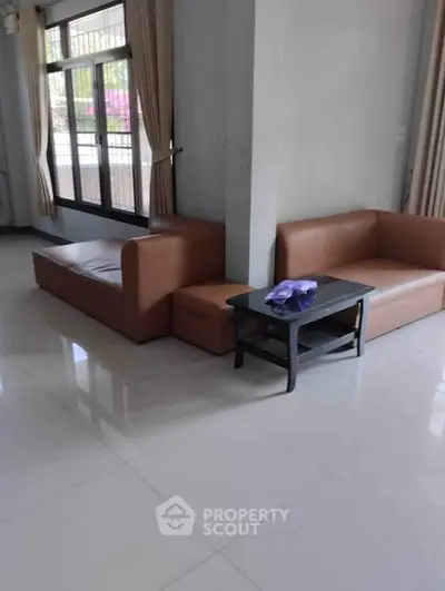 Spacious living room with modern brown sofas and large windows