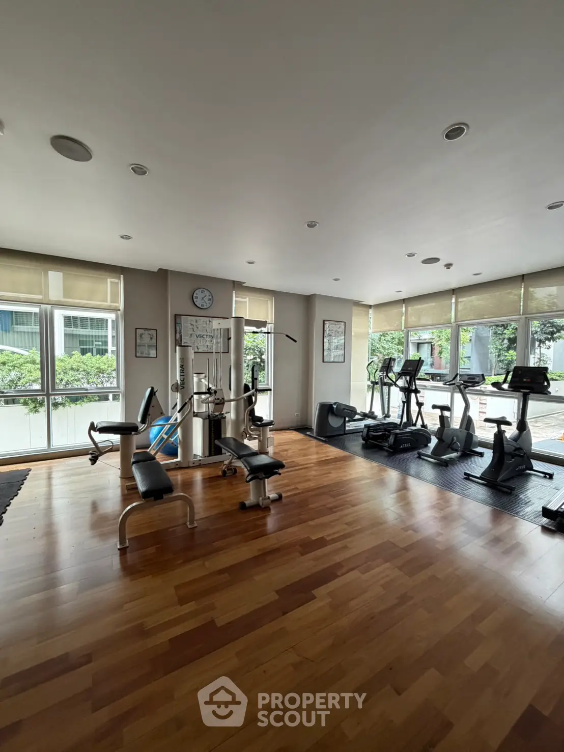 Spacious gym with modern equipment and large windows in a residential building.
