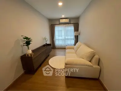Modern living room with cozy white sofa and wooden flooring, featuring elegant decor and natural light.