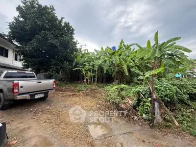 Spacious land plot with lush greenery and potential for development, featuring a parked vehicle and clear skies.