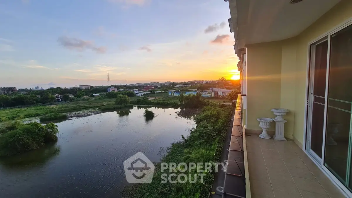 Stunning sunset view from a spacious balcony overlooking serene water and lush greenery.