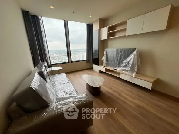 Modern living room with large window and city view, featuring sleek furniture and wooden flooring.