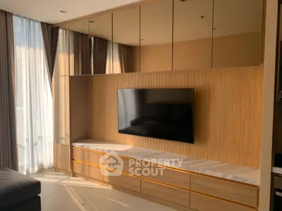 Modern living room with sleek TV unit and mirrored cabinets, bathed in natural light.