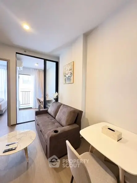 Modern living room with cozy sofa and dining area, featuring elegant decor and natural light.