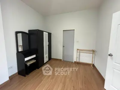 Spacious empty room with wooden flooring and modern black wardrobe