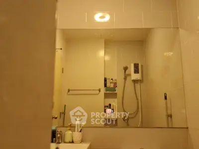 Cozy bathroom with shower and large mirror, featuring modern fixtures and ample storage space.