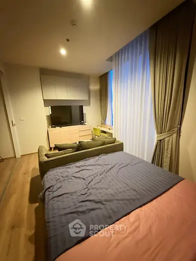 Cozy bedroom with modern decor and large window draped with elegant curtains, featuring a stylish bed and TV unit.