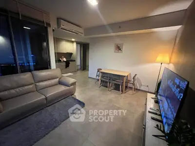Modern living room with cozy seating and dining area, open kitchen layout, and ambient lighting.