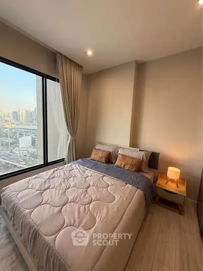 Modern bedroom with city view and cozy decor in high-rise apartment.