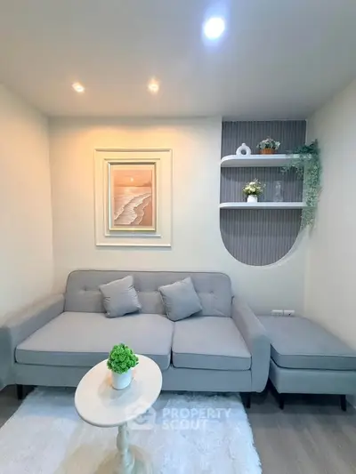 Cozy living room with modern gray sofa, elegant wall art, and stylish shelving, perfect for relaxation.