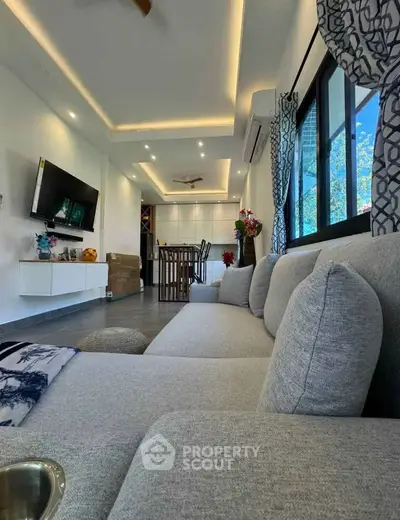 Modern living room with sleek design, large sofa, and wall-mounted TV, perfect for relaxation and entertainment.