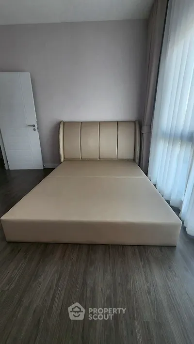 Spacious bedroom with elegant bed and floor-to-ceiling windows for natural light.