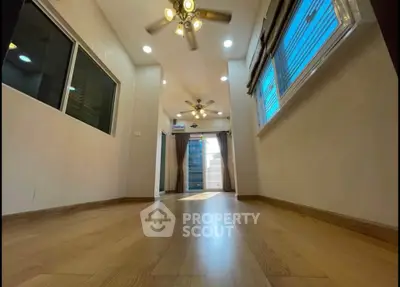 Spacious interior with wooden flooring and ceiling fans, abundant natural light through large windows.