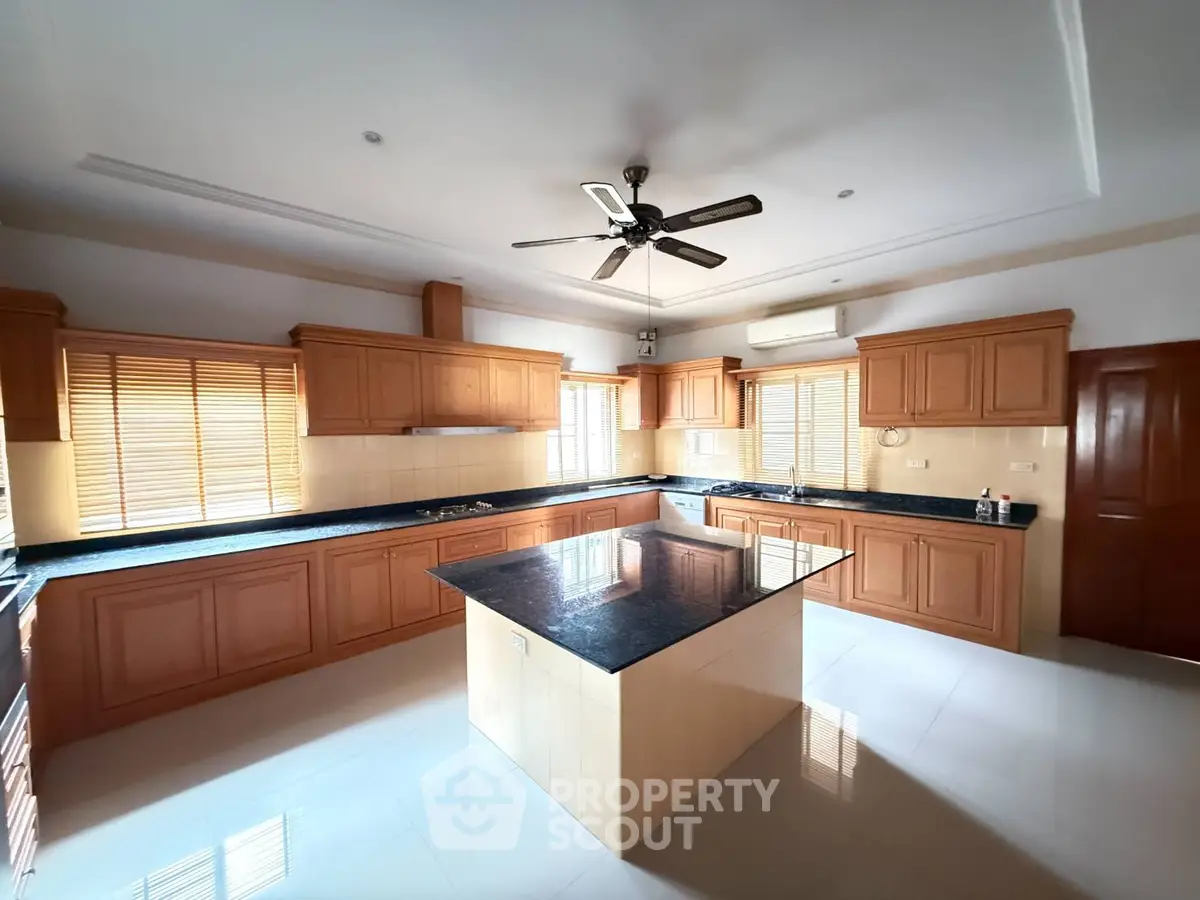 Spacious kitchen with island and wooden cabinets, featuring a ceiling fan and ample natural light.