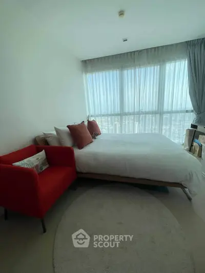 Bright bedroom with large window and modern decor in high-rise apartment.