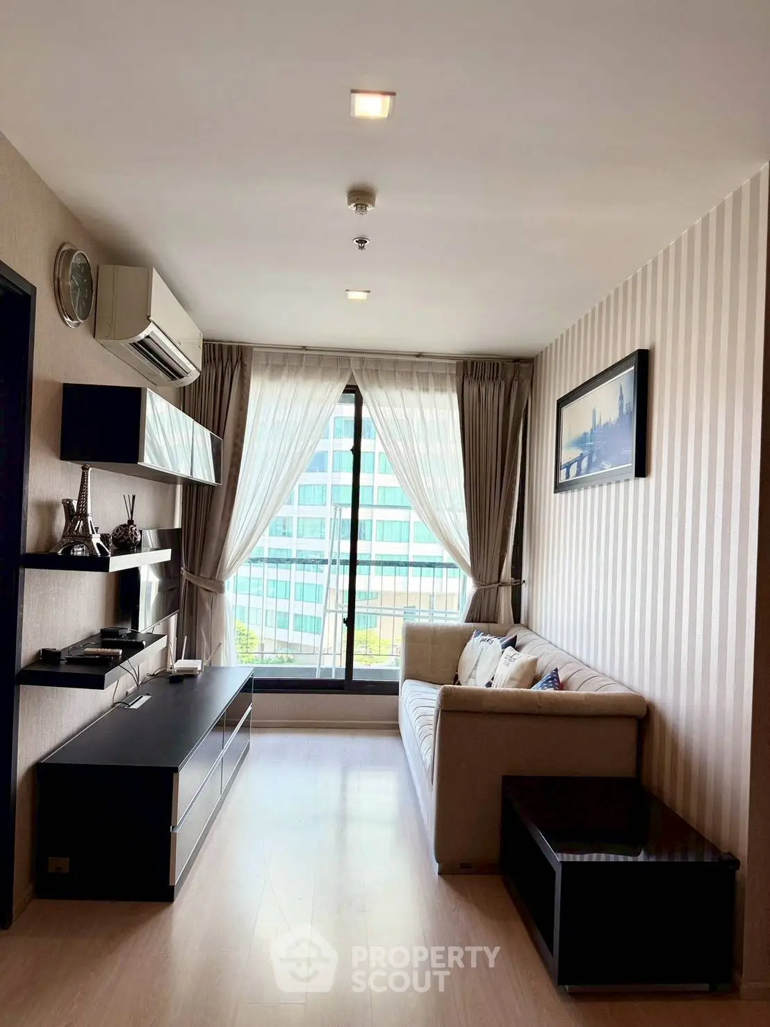 Modern living room with stylish decor and large window offering natural light and city view.