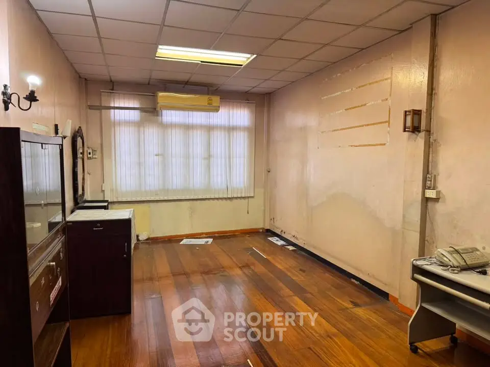 Spacious room with wooden flooring and air conditioning, ideal for office or study setup.