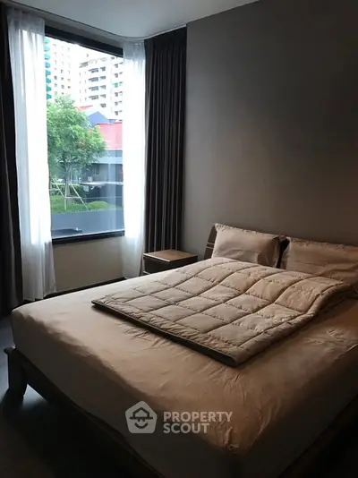 Cozy bedroom with large window offering city view, featuring a comfortable bed and modern decor.