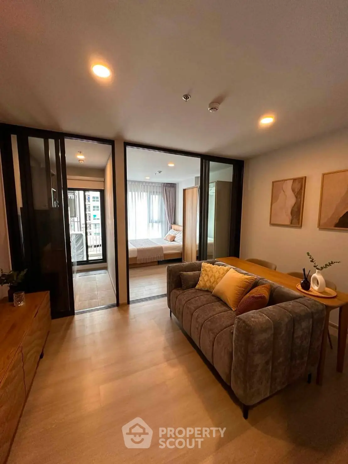 Modern living room with cozy sofa and view into stylish bedroom, featuring elegant decor and natural light.