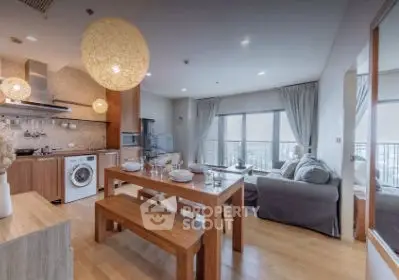 Spacious open-plan living room with modern kitchen and dining area, featuring large windows and stylish decor.