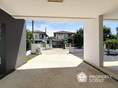 Spacious driveway leading to modern suburban homes with lush greenery.